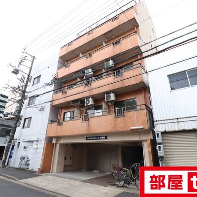 ビルの合間に際立つカラーのマンションです。